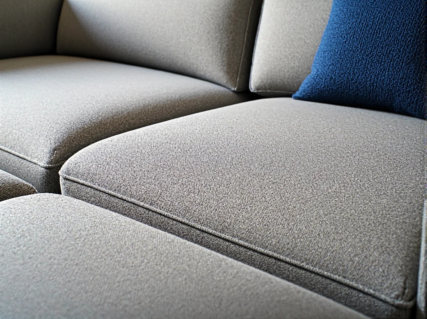 Nowoczesna szara sofa modułowa w małym salonie, idealnie dopasowana do ograniczonej przestrzeni.